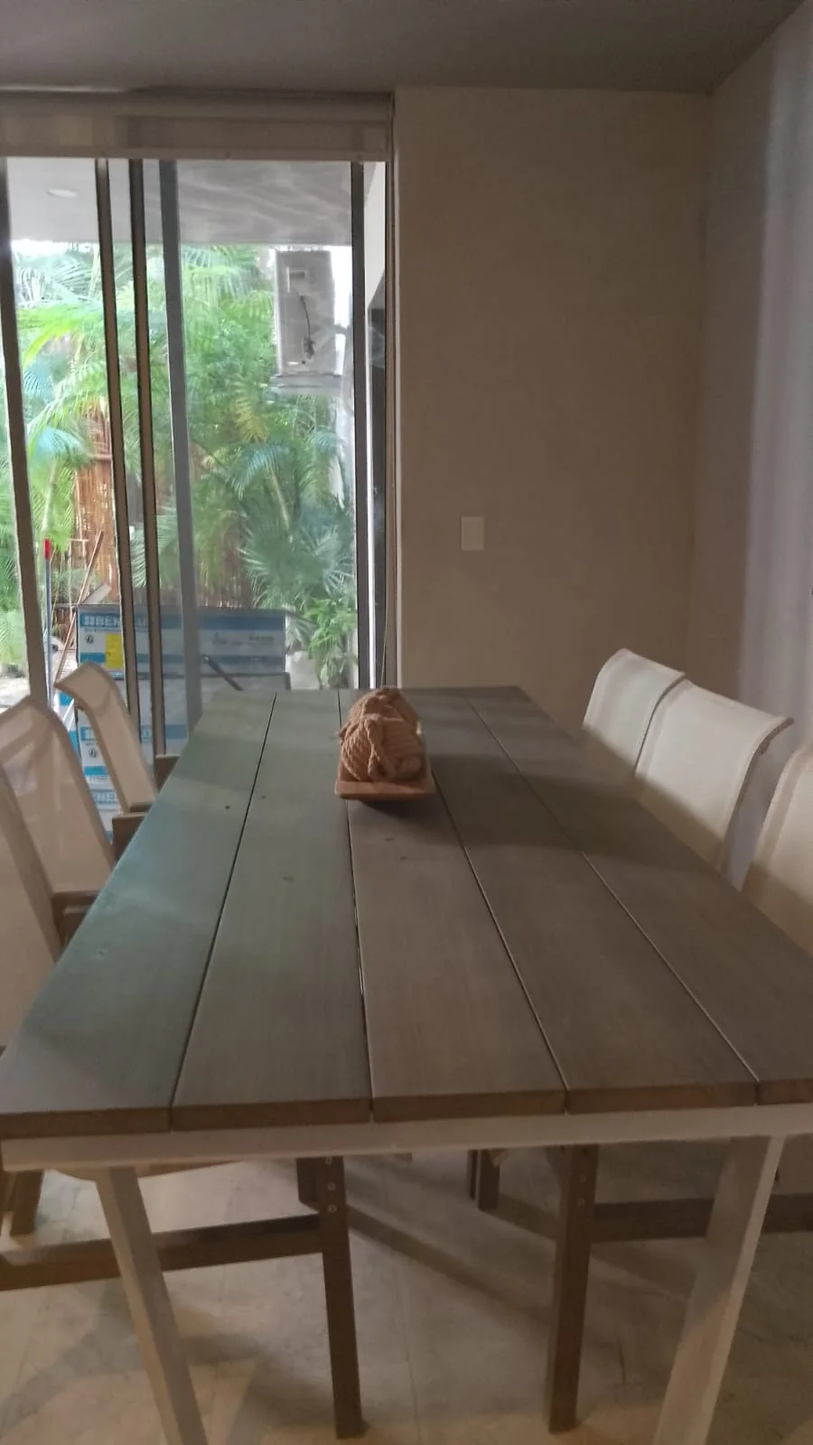 Comedor de madera frente a ventanales con vegetación en el departamento Artia, Aldea Zamá